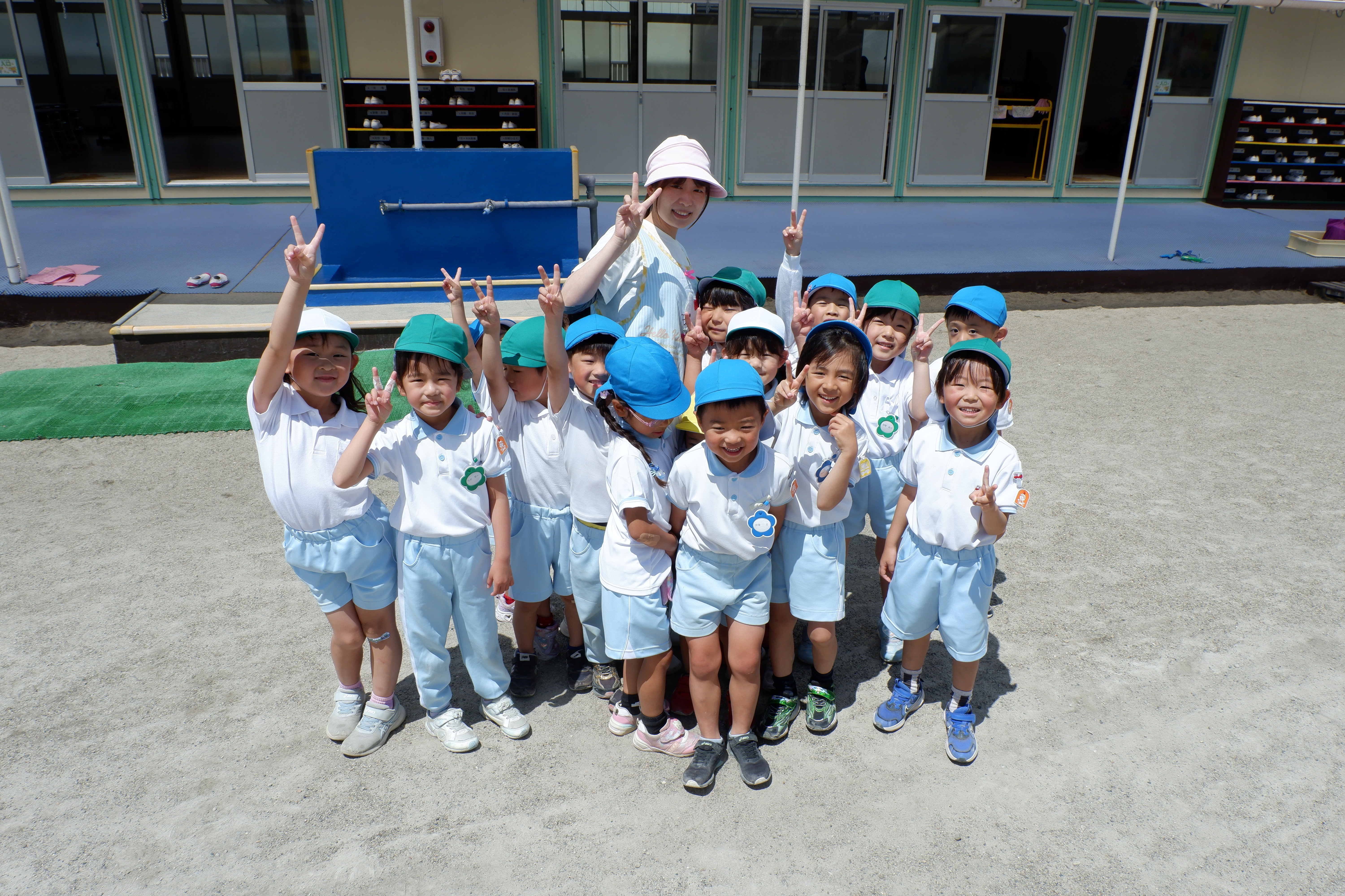 園庭で先生と記念撮影をする子どもたち