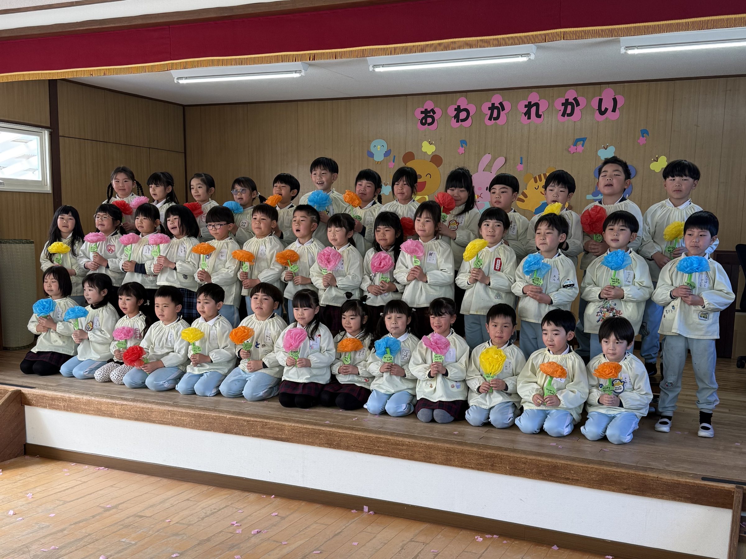お別れ会で花を持つ子どもたち