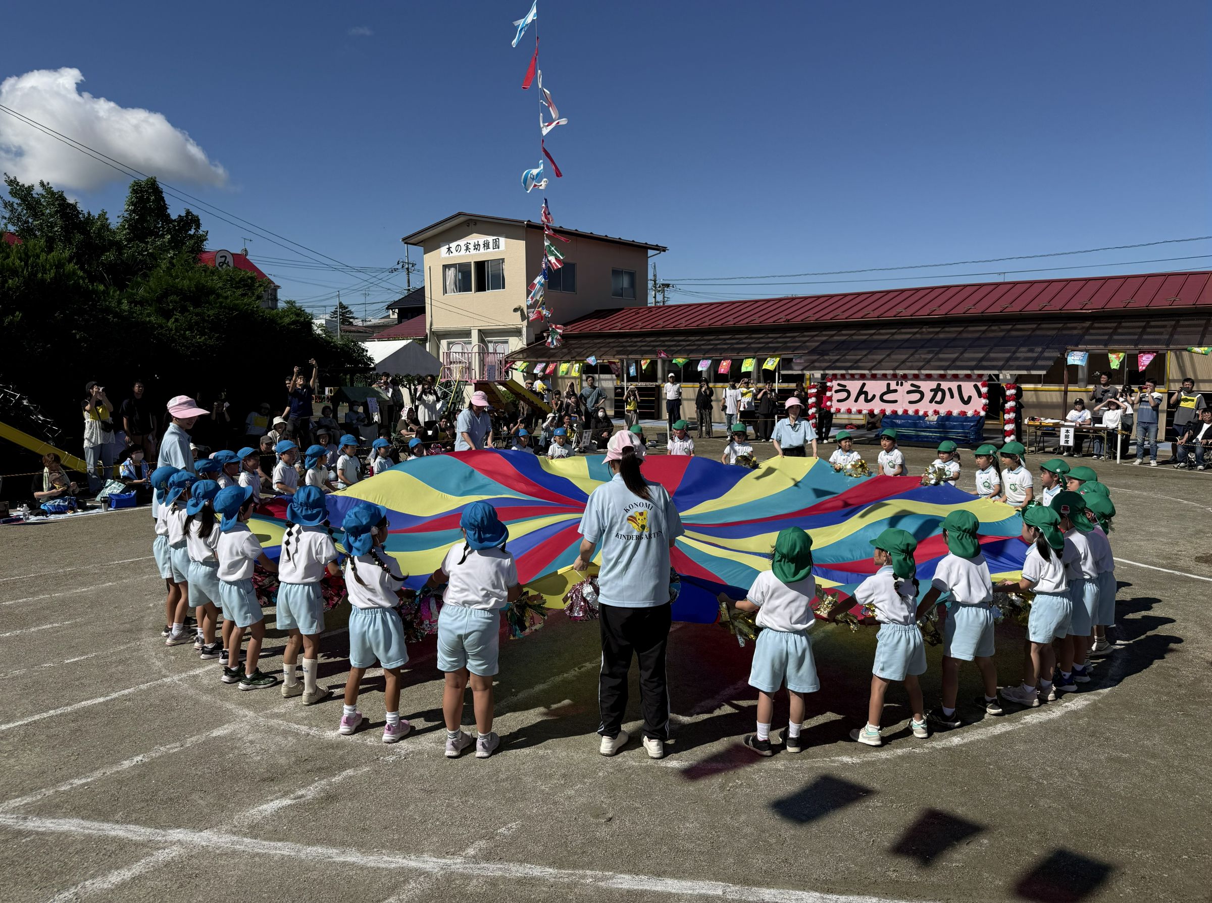 運動会でパラシュートを広げる子どもたち